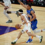 Suns guard Devin Booker driving into the lane with Mavericks forward Grant Williams defending him (Jeremy Schnell/Arizona Sports)