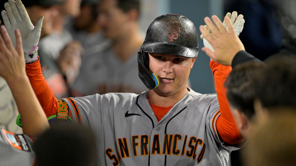 Joc Pederson #23 of the San Francisco Giants is congratulated by teammates in the dugout after hitt...