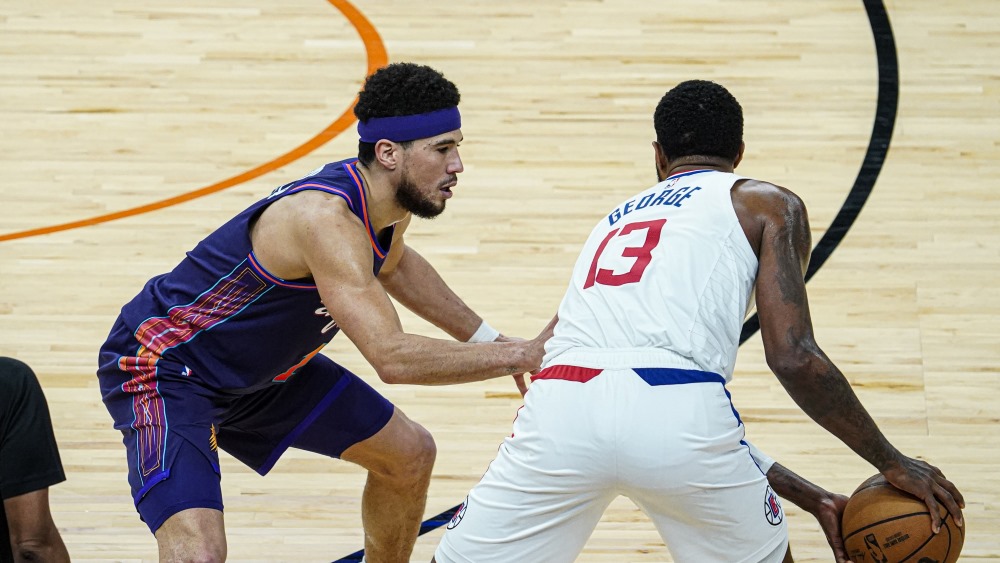 Suns guard Devin Booker defends Clippers forward Paul George...