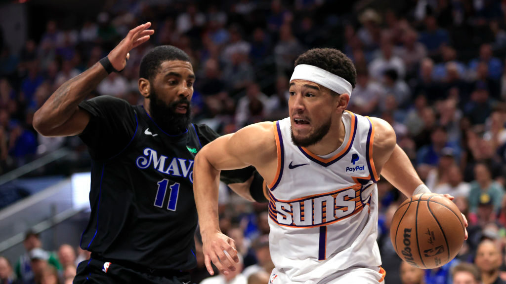 Devin Booker #1 of the Phoenix Suns drives inside as  Kyrie Irving #11 of the Dallas Mavericks defe...