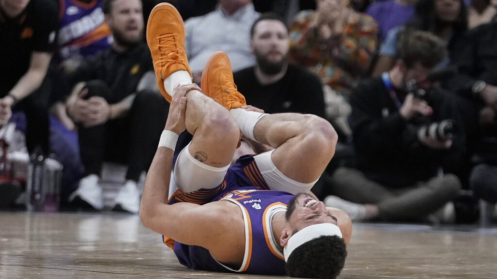 Phoenix Suns guard Devin Booker (1) holds his leg after injuring it during the second half of an NB...