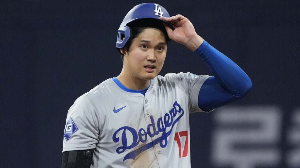 Los Angeles Dodgers designated hitter Shohei Ohtani takes his helmet off after making it to first o...