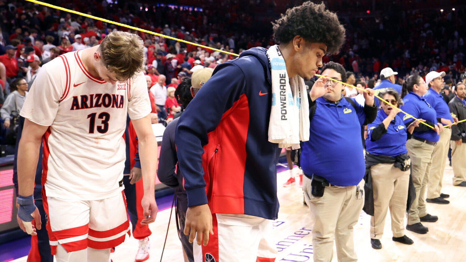 Motiejus Krivas #13 and Koa Peat #10 of the Arizona Wildcats walk off the court after losing to the...