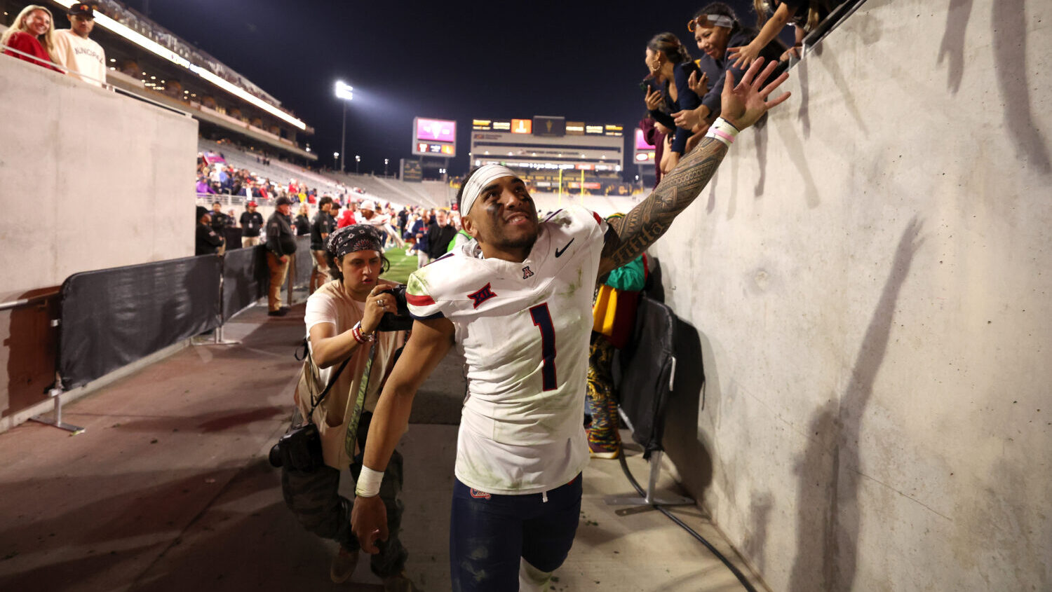 TEMPE, ARIZONA - NOVEMBER 28: Quarterback Noah Fifita #1 of the Arizona Wildcats high fives fans af...