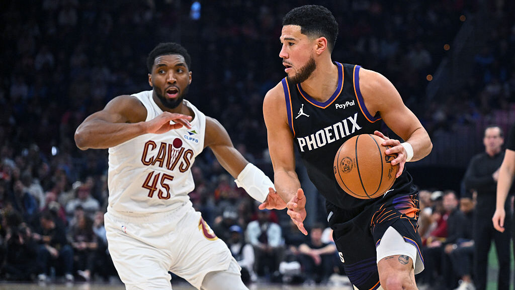 Devin Booker #1 of the Phoenix Suns drives to the basket around Donovan Mitchell #45 of the Clevela...