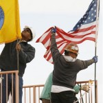 Robert Bravo, Jr., left, adjusts the Hualapai Nation flag while other workers place the American flag on the Skywalk before the rollout of the Skywalk on the Hualapai Indian Reservation in Grand Canyon West, Ariz. (Associated Press)