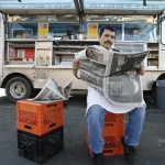 Filiberto Magana reads about election news in a newspaper outside his food truck the day after Barack Obama won the presidential election in Detroit, Wednesday, Nov. 5, 2008. (AP Photo/Paul Sancya)