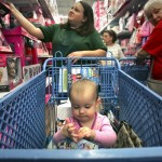 Jessica Luu, left, looks for deals as her friend's baby, Kaylee Oliver, inspects a toy in the shopping cart, as shoppers at Toys "R" Us at The Forum at Olympia Parkway in Selma, Texas look for the best savings on Black Friday, Nov. 28, 2008. (AP Photo/San Antonio Express-News, Bob Owen)