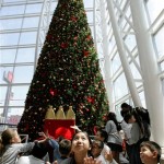 Children play next to a Christmas tree at a shopping mall in Santiago, Tuesday, Dec. 2, 2008. (AP Photo/Santiago Llanquin)
