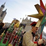 A traditional dressed man holds a star as he stands beside a Christmas crib during an annual competition of Christmas cribs on the Market Square in Krakow, Poland, Thursday, Dec. 4, 2008. (AP Photo/Pawel Ulatowski)