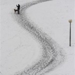  A woman walks her dog on a snowy way in the Olympic park in Munich, southern Germany, during winter weather with temperatures around the freezing point on Friday, Dec. 12, 2008. (AP Photo/Christof Stache)