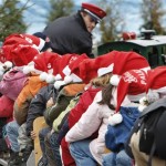 Children of a day-care center in Stuttgart wearing Santa Claus caps make a round on a miniature railway on the christmas market in Stuttgart, Germany, Friday, Dec. 12, 2008, as driver Marcel Tamas glances at his passengers. (AP Photo/Thomas Kienzle)