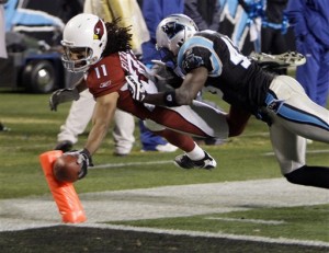 Arizona Cardinals' Larry Fitzgerald (11) reaches the ball over the goal line for a touchdown as Carolina Panthers' Chris Harris (43) defends during the second quarter of an NFL divisional playoff football game in Charlotte, N.C., Saturday, Jan. 10, 2009. (AP Photo/Chuck Burton)