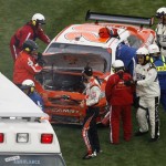 Joey Logano, center, looks at his damaged car as he is helped by emergency workers after a crash during the NASCAR Daytona 500 auto race at Daytona International Speedway in Daytona Beach, Fla., Sunday, Feb. 15, 2009. (AP Photo/Glenn Smith)