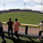 Fans watch from over the outfield fence as San Diego Padres outfielders chase a ball during the fifth inning of a spring training baseball game against the Seattle Mariners on Thursday, Feb. 26, 2009, in Peoria, Ariz. The game ended in a 4-4 tie after 10 innings. (AP Photo/Charlie Riedel)