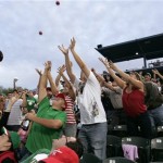 Baseball fans reach for toy balls tossed into the stands during a exhibition spring baseball game between Mexico and the Arizona Diamondbacks Wednesday, March 4, 2009, in Tucson, Ariz. (AP Photo/Elaine Thompson)