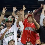 Baseball fans reach for toy baseballs tossed into the stands during an exhibition spring baseball game between Mexico and the Arizona Diamondbacks, Wednesday, March 4, 2009, in Tucson, Ariz. (AP Photo/Elaine Thompson)