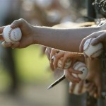 Fans stick their hands through an opening in the fence to get autographs at the New York Yankees spring training facility prior to the Yankees spring baseball game against the Detroit Tigers at Steinbrenner Field in Tampa, FL. (AP Photo/Kathy Willens)
