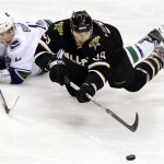 Dallas Stars Joel Lundqvist (39) reaches for the puck against Vancouver Canucks Alex Burrows (14) during the third period of the NHL hockey game in Dallas, Tuesday, March 24, 2009. (AP Photo/LM Otero)