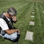 In this May 17, 2009 photo, Joe Landaker wipes away tears while visiting the grave of his son, Jared, at Riverside National Cemetery in Riverside, Calif. Landaker is among more than 300 volunteers who honor those buried in the cemetery by reading their names leading up to Memorial Day each year. (AP Photo/Branimir Kvartuc)