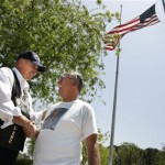 In this May 17, 2009 photo, Richard Blackaby, left, an Army veteran, and Joe Landaker, whose son, a Marine helicopter pilot, died in Iraq, shake hands after they read names of the military dead buried at Riverside National Cemetery in Riverside, Calif. The men are among more that 400 volunteers who honor veterans this way each year leading up to Memorial Day. (AP Photo/Branimir Kvartuc)