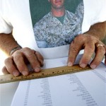 In this May 17, 2009 photo, Joe Landaker wears a T-shirt bearing his son's image as he reads the names of veterans buried at Riverside National Cemetery in Riverside, Calif. Landaker is among more than 400 volunteers who honor the cemetery's military dead by reading their names leading up to Memorial Day. His son, Jared, who died on Feb. 7, 2007 during his last mission in Iraq as a Marine helicopter pilot, is buried in the cemetery. (AP Photo/Branimir Kvartuc)