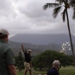 President Barack Obama waves to the crowd as fireworks explode in the distance after his golf game at Mid Pacific Country Club in Kailua, Hawaii Thursday, Dec. 31, 2009. The Obamas are in Hawaii for the holidays.(AP Photo/Alex Bran)