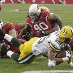 Green Bay Packers' Ryan Grant (25) scores a touchdown as he gets past Arizona Cardinals' Darnell Dockett (90) and Clark Haggans, left, in the first quarter of an NFL football game Sunday, Jan. 3, 2010, in Glendale, Ariz. (AP Photo/Ross D. Franklin)