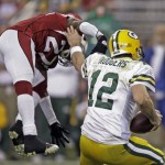 Green Bay Packers' Aaron Rodgers (12) evades the rush of Arizona Cardinals' Michael Adams (27) during the first half of an NFL wild-card playoff football game Sunday, Jan. 10, 2010, in Glendale, Ariz. (AP Photo/Paul Connors)
