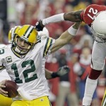 Green Bay Packers' Aaron Rodgers (12) gets away from the rush of Arizona Cardinals' Michael Adams (27) during the first half of an NFL wild-card playoff football game Sunday, Jan. 10, 2010, in Glendale, Ariz. (AP Photo/Ross D. Franklin)