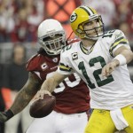 Green Bay Packers' Aaron Rodgers (12) throws while being rushed by Arizona Cardinals' Darnell Dockett (90) during the first half of an NFL wild-card playoff football game Sunday, Jan. 10, 2010, in Glendale, Ariz. (AP Photo/Ross D. Franklin)