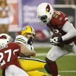 Green Bay Packers quarterback Aaron Rodgers watches Arizona Cardinals' Karlos Dansby (58) run back a fumble after Rodgers was hit by Michael Adams (27) during overtime of an NFL wild-card playoff football game Sunday, Jan. 10, 2010, in Glendale, Ariz. Arizona won 51-45. (AP Photo/Matt York)