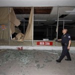 Calexico police officer Luis Casillas walks past windows broken out of a downtown Calexico, Calif. store front after a powerful earthquake centered in Mexico swayed buildings from Los Angeles to Tijuana Sunday, April 4, 2010. (AP Photo/Denis Poroy)