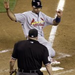 St. Louis Cardinals' Albert Pujols ,top, slides safely across homeplate as umpire Marty Foster, bottom, looks on against the Arizona Diamondbacks in the ninth inning of a baseball game Monday, April 19, 2010, in Phoenix. The Cardinals won 4-2. (AP Photo/Paul Connors)