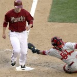 Arizona Diamondbacks' Mark Reynolds, left, steps on home plate before Philadelphia Phillies catcher Carlos Ruiz, right, can apply the tag in the eighth inning of a baseball game Sunday, April 25, 2010, in Phoenix. (AP Photo/Paul Connors)