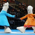In this Aug. 17, 2004, file photo, the Olympic mascots Athena, right, and Phevos fence during the interval between two semifinal rounds at the 2004 Olympic Games at the Helliniko fencing hall in Athens. Phevos and Athena, Athens' offerings in 2004, were named for Greek gods and were an affront to design, new and old. Their little heads sat atop dinosaur-long necks, and their feet resembled flippers--really, really big flippers. (AP Photo/Michael Sohn, File)
