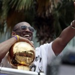 Holding the NBA championship trophy, Los Angeles Lakers' Kobe Bryant flashes the victory sign during a parade in downtown Los Angeles on Monday, June 21, 2010. (AP Photo/Richard Vogel)