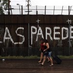 Two woman walk along the U.S.-Mexico border showing graffiti that reads "the walls" in Nogales, Sonora, Mexico, Tuesday, July 27, 2010. Arizona's new immigration law SB1070 takes effect Thursday, July 29. (AP Photo/Jae C. Hong)