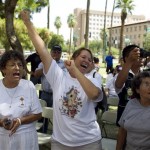 Maria Uribe, center, and other opponents of Arizona State Bill 1070 celebrate outside the Arizona State Capitol building in Phoenix on Wednesday, July 28, 2010 as they hear the news that U.S. District Judge Susan Bolton issued an injunction for the key portions of the controversial bill. (AP Photo/Houston Chronicle, Nick de la Torre)