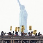 With the Statue of Liberty behind them, a coalition of immigrant groups and their supporters march in the hundreds across the Brooklyn Bridge, Thursday July 29, 2010, in New York. Protesters are calling for the full repeal of Arizona's immigration law, saying it fuels a climate of racism. (AP Photo/Seth Wenig)