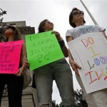 Naomi Wallace, right, is joined by her daughters Tegan McLeod, left, and Caitlin McLeod, center, as they protest the Arizona immigration law outside the federal courthouse in Louisville, Ky., Thursday, July 29, 2010. (AP Photo/Ed Reinke)