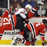 New Jersey Devils' Brian Rolston (12) is tripped as Phoenix Coyotes' Sami Lepisto (18) and Devils' David Clarkson, right, eye the puck during the first period of an NHL hockey game Wednesday, Dec. 15, 2010, in Newark, N.J. (AP Photo/Bill Kostroun)