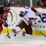 Phoenix Coyotes' Eric Belanger, right, is checked to the ice by New Jersey Devils' Travis Zajac during the third period of an NHL hockey game Wednesday, Dec. 15, 2010, in Newark, N.J. The Devils defeated the Coyotes 3-0. (AP Photo/Bill Kostroun)