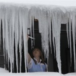 A woman removes icicles at a roof of a house in Winterberg, Germany, Friday, Dec. 10, 2010. The weather forecast predicts temperatures below the freezing point and snowfalls. (AP Photo/Frank Augstein)