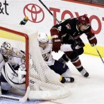 Nashville Predators' Chris Mueller, center, falls as Phoenix Coyotes' Shane Doan, right, tries to move the puck as Predators goalie Pekka Rinne, of Finland, defends the net during the first period of an NHL hockey game Tuesday, Jan. 18, 2011, in Glendale, Ariz. (AP Photo/Matt York)