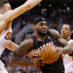 Miami Heat's LeBron James, middle, drives past Phoenix Suns' Miles Plumlee, left, and Channing Frye, right, during the first half of an NBA basketball game Tuesday, Feb. 11, 2014, in Phoenix. (AP Photo/Ross D. Franklin)