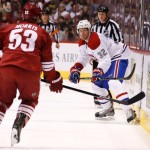 Montreal Canadiens' Travis Moen (32) flips the puck past Phoenix Coyotes' Derek Morris (53) during the first period of an NHL hockey game on Thursday, March 6, 2014, in Glendale, Ariz. (AP Photo/Ross D. Franklin)