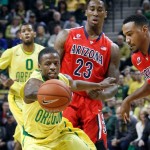 As Oregon's Mike Moser looks on, rear left, teammate Johnathan Loyd battles Arizona's Rondae Hollis-Jefferson and Jordin Mayes, right, for a loose ball during the first half of an NCAA college basketball game in Eugene, Ore. on Saturday, March 8, 2014. (AP Photo/Chris Pietsch)