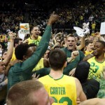 Oregon fans storm the court to celebrate with the Duck basketball team including Waverly Austin, center left, and Elgin Cook, right after they defeated Arizona 64-57 in an NCAA college basketball game in Eugene, Ore. on Saturday, March 8, 2014. (AP Photo/Chris Pietsch)