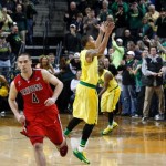 Arizona's T.J. McConnell, left, runs off the court as Oregon's Joseph Young leaps in the air in celebration after the Ducks defeated the Wildcats 64-57 in an NCAA college basketball game in Eugene, Ore. on Saturday, March 8, 2014. (AP Photo/Chris Pietsch)